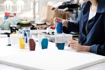 Female artist mixing acrylic paints for abstract art canvas