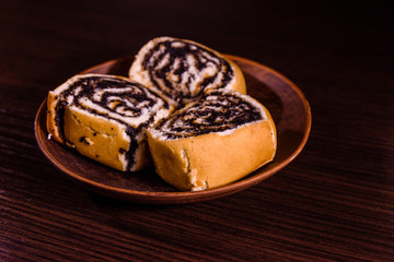 Ceramic plate with poppy seed buns on dark wooden table
