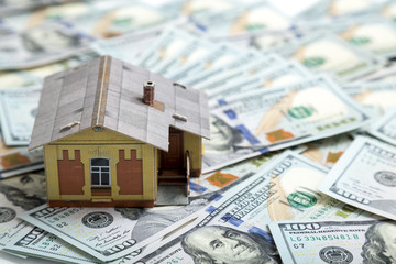 Mortgage concept. house and money. Miniature house model on pile of dollar banknote