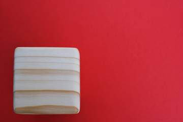 Wooden block on red background. Wood block with space for text. Wood cube as template for your ideas.