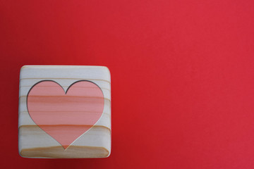 Wooden block with heart on red background. Valentines day background with space for text.