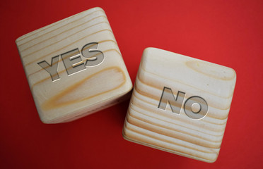 Two wood blocks with text: yes an no on red background. Decision making concept.