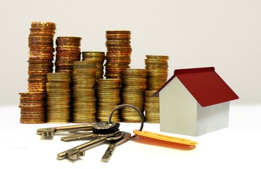 Stacks of coins with miniature house and house keys as mortgage and investment concept