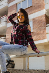 Fototapeta na wymiar Stylish young brunette woman in sunglasses posing outdoors