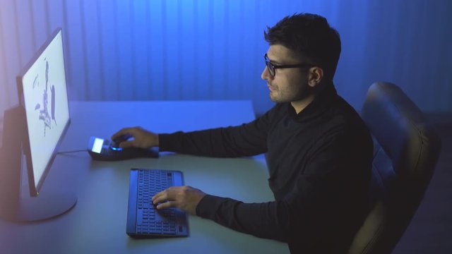 The man works with a 3d graphics in a computer. evening night time