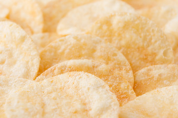 Crunchy potato chips with spices as background, closeup, top view.