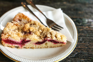 Piece of sweet pie with dessert fork on a plate on a wooden surface in the cafe