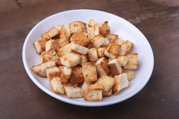 Delicious crispy croutons, crumbs of bread in white plate. ready for cooking.