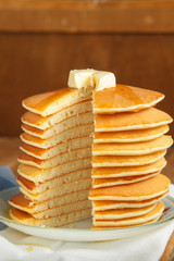 Vertical image of cut stack of pancake with honey and butter on top. Close up