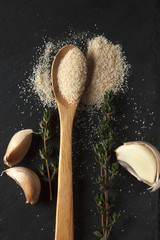 Composition of garlic powder, sprigs of thyme and cloves on black slate board