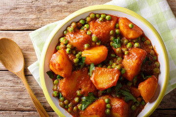 Home Indian food: Aloo Matar - potatoes, green peas and spicy sauce closeup. horizontal top view