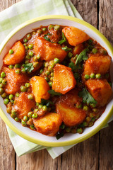Spicy Aloo Matar potatoes, green peas and spices close-up. Vertical top view