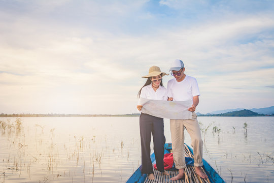 Travel man and woman with mapk standing on tail of the boat with lake and mountain view, Travel concept