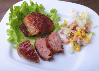 Marinated roaste chicken breasts cooked on BBQ and served with fresh salad on white plate, close-up.