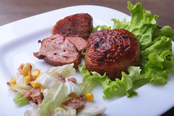 Marinated roaste chicken breasts cooked on BBQ and served with fresh salad on white plate, close-up.