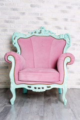 Pink vintage luxury armchair on white brick wall background. Elegant furniture.