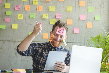 Stressed man with message on sticky notes over his face in office.