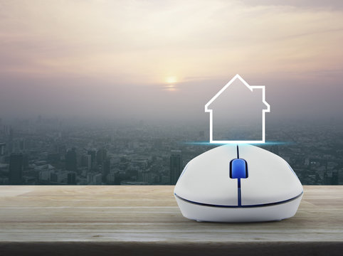 House icon with copy space with wireless computer mouse on wooden over modern city tower at sunset, vintage style, Real estate concept