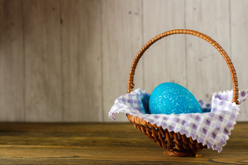 Easter egg in the basket. Wooden background, place for your text.