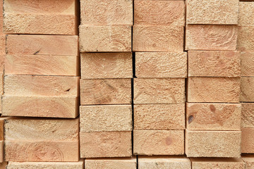 Texture of folded wooden planks in a warehouse with a forest. View from the end