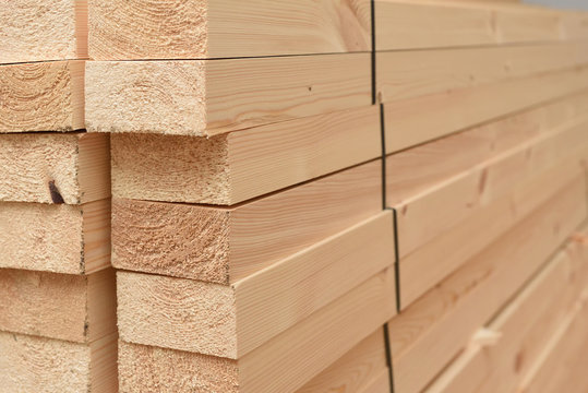 Many folded wooden planks in a warehouse with a forest