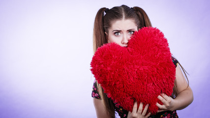 Scared woman holding heart shaped pillow