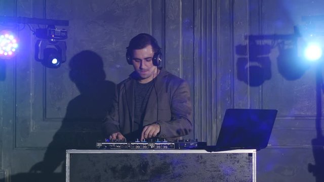 Man DJ in dark suit play music on a Dj's mixer