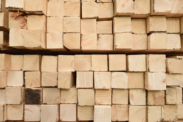 Texture of folded wooden planks in a warehouse with a forest. View from the end