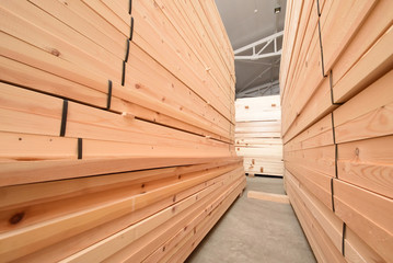 Many folded wooden planks in a warehouse with a forest