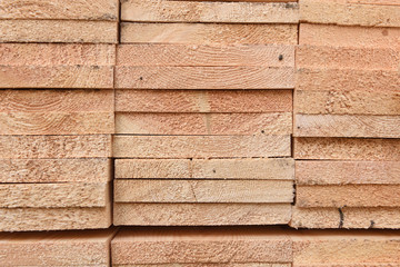 Texture of folded wooden planks in a warehouse with a forest. View from the end