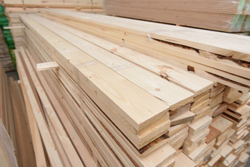 Many folded wooden planks in a warehouse with a forest
