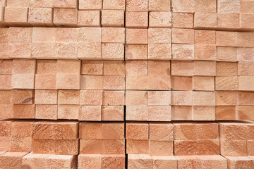 Texture of folded wooden planks in a warehouse with a forest. View from the end