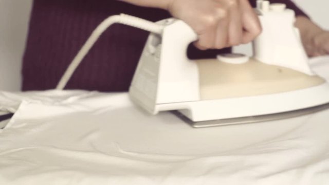 Closeup of female hands ironing white with electric iron