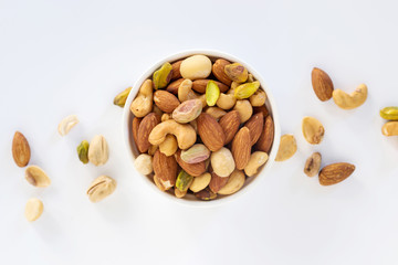 Healthy food and snack : mixed nuts in white ceramic bowl on white background from above,...