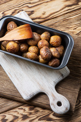 Baked homemade potatoes are in a metallic form on a wooden background