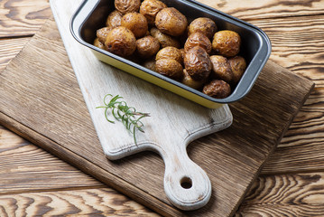 Baked homemade potatoes are in a metallic form on a wooden background