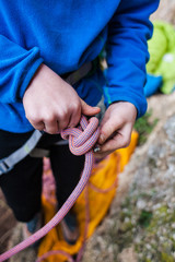 A rock climber tie a knot for insurance.
