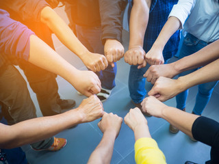 Closeup image of many people putting their fists together as symbol of unity. Teamwork Concept.