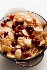 delicious crispy cornflakes with cranberries in bowl on white background, closeup, healthy breakfast 