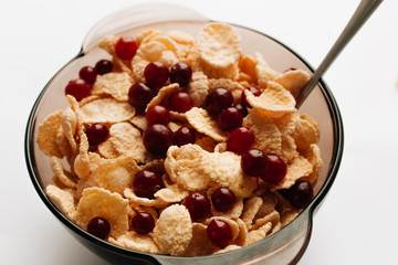 delicious crispy cornflakes with cranberries in bowl on white background, closeup, healthy breakfast 