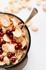 delicious crispy cornflakes with cranberries in bowl on white background, closeup, healthy breakfast 