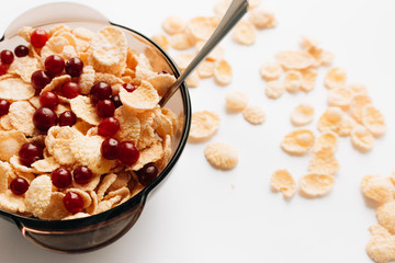delicious crispy cornflakes with cranberries in bowl on white background, closeup, healthy breakfast 