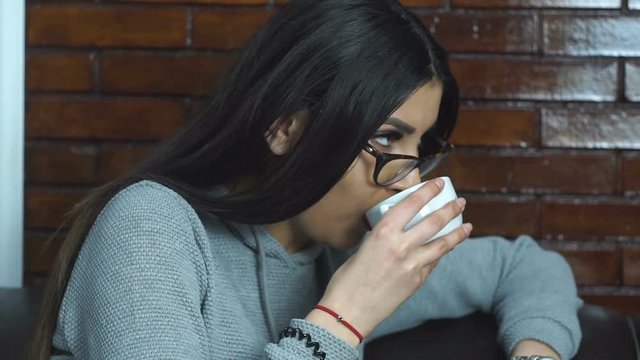 Yong girl drinks coffee and talking sitting on coush.