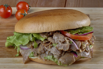 doner meat in hamburger bread,close up of kebab sandwich on wooden background
