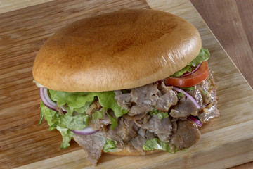 doner meat in hamburger bread,close up of kebab sandwich on wooden background
