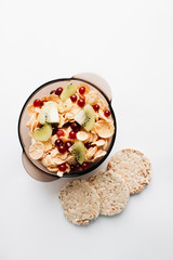 crisp bread and delicious crispy cornflakes with kiwi and berries in bowl over white background,  healthy breakfast