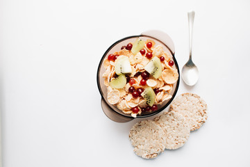 crisp bread and delicious crispy cornflakes with kiwi and berries in bowl over white background,  healthy breakfast