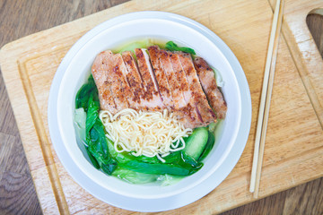 Instant Noodles with fried Pork Cutlet with Pak Choy or Chinese Cabbage in white bowl and Plate on wooden table