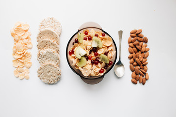 crisp bread, almonds and delicious crispy cornflakes with kiwi and berries in bowl over white background,  healthy breakfast