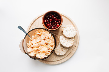 delicious crispy cornflakes in bowl with cranberries and almonds  on white background,  healthy...